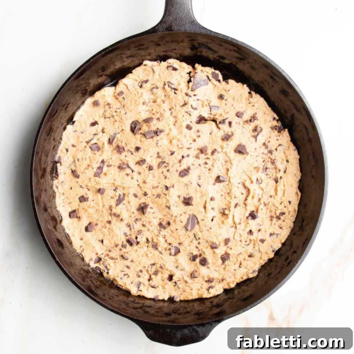 Decadent Vegan Gluten-Free Chocolate Chunk Skillet Cookie 9 Thick, luscious chocolate chunk cookie dough batter is carefully spread into a cast iron skillet, ready for baking.