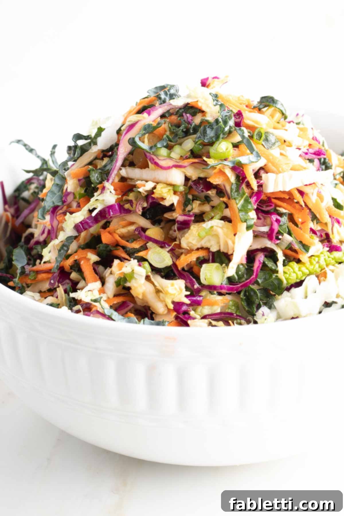 A large bowl generously filled with a vibrant, colorful mix of shredded vegetables for the slaw.