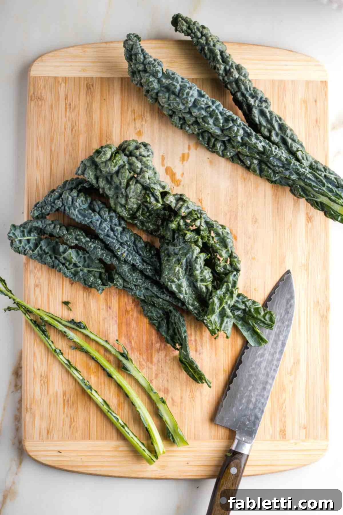 Lacinato kale with its tough stems removed, laid out on a wooden cutting board.