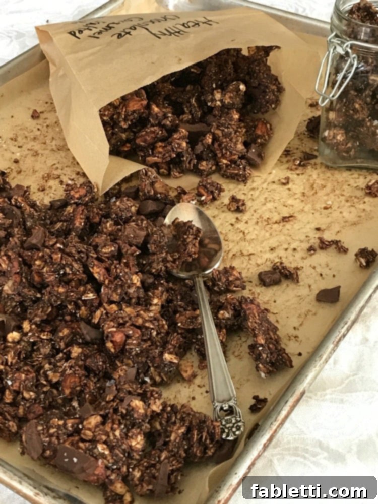 Nourishing Chocolate Oat Granola 7 Chocolate granola being spooned into a small paper bag.