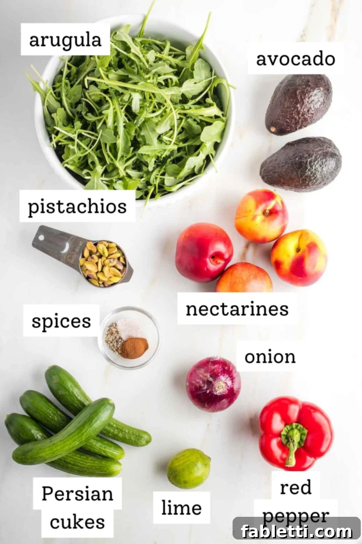 Vibrant Nectarine Arugula Salad 4 Fresh, vibrant ingredients for nectarine salad: arugula, sliced nectarines, avocados, cucumbers, red pepper, red onion, pistachios, and lime.