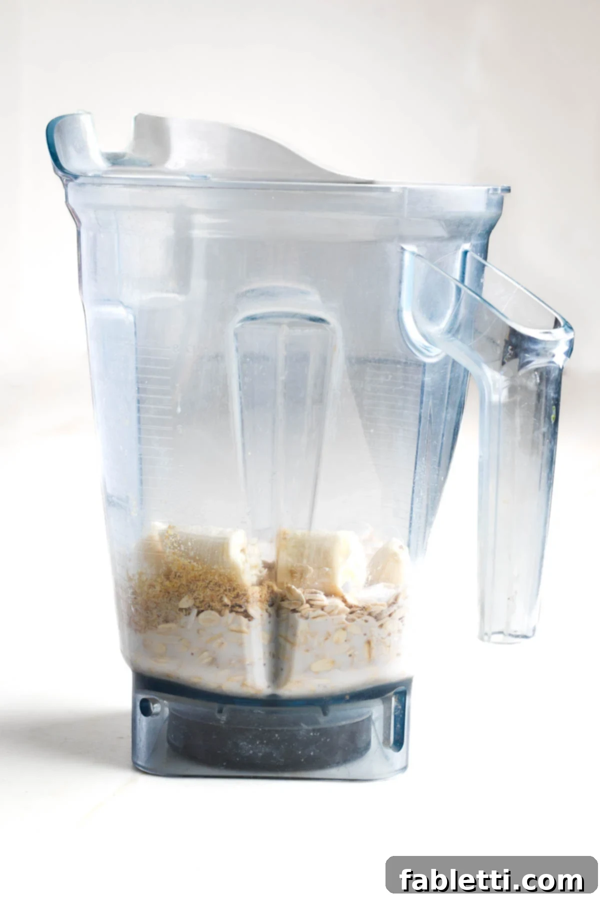Effortless Vegan Banana Oat Blender Pancakes 4 Blender pitcher with milk, oats, banana pieces visible.