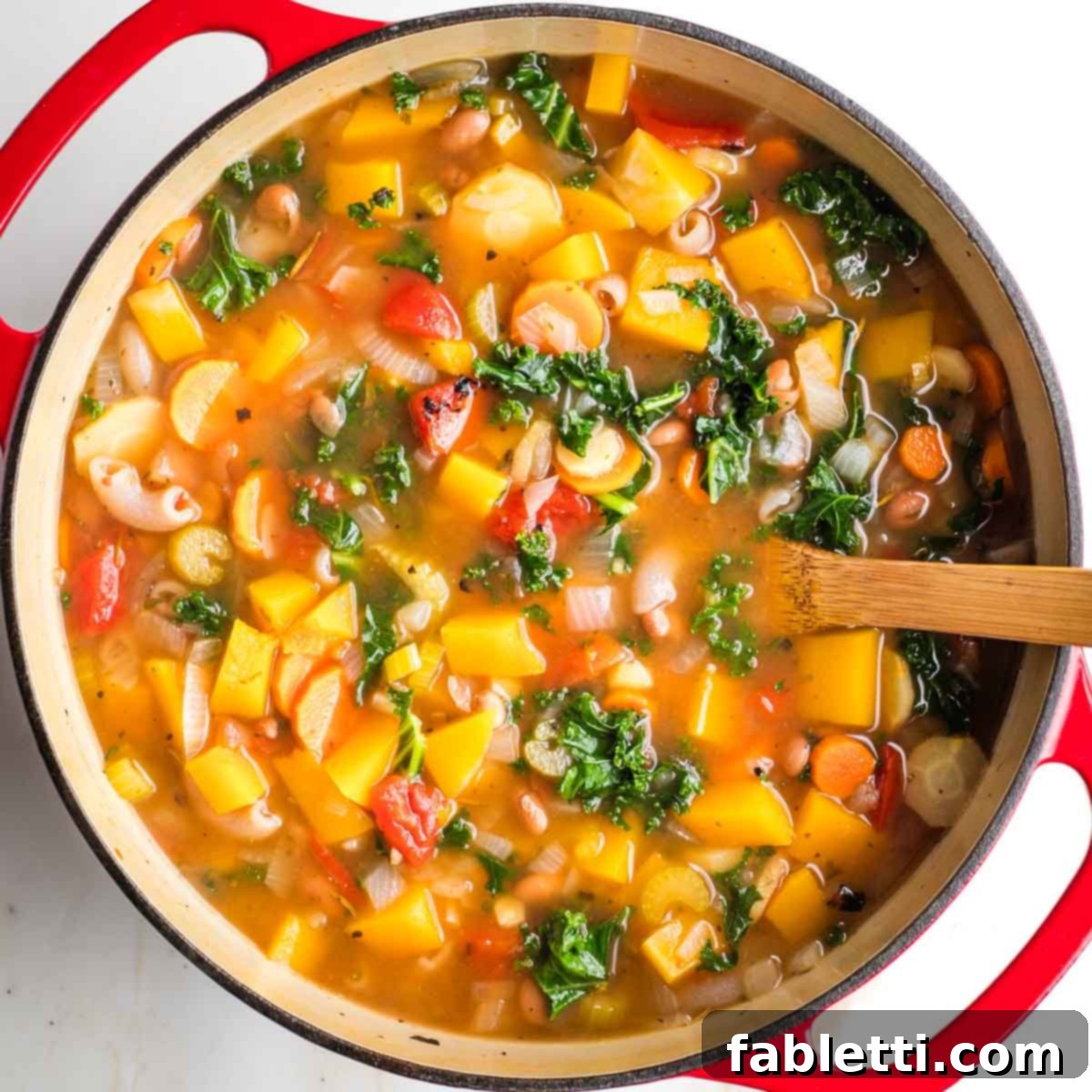 Hearty Fall Vegan Minestrone 11 Minestrone with chunks of root veggies and butternut squash in broth in a dutch oven.