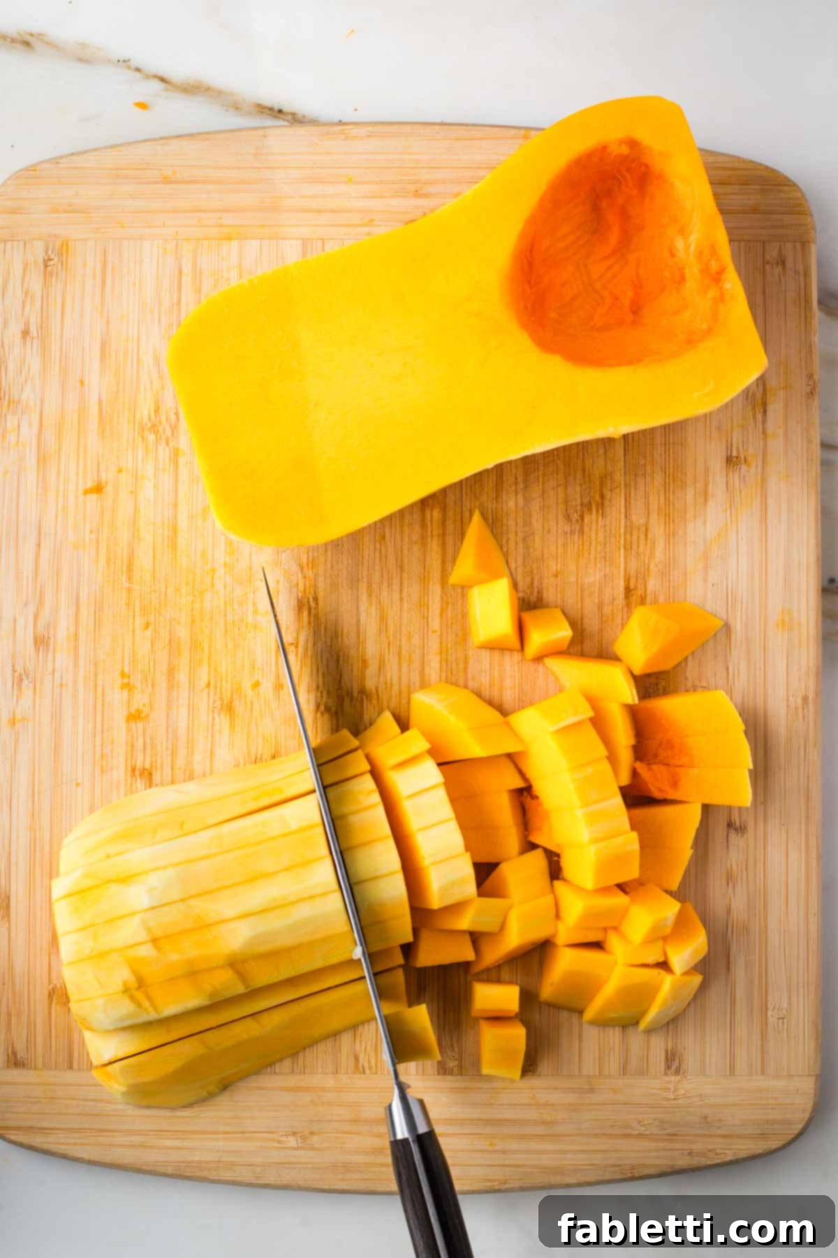 Hearty Fall Vegan Minestrone 5 Cutting peeled butternut squash into small dice.