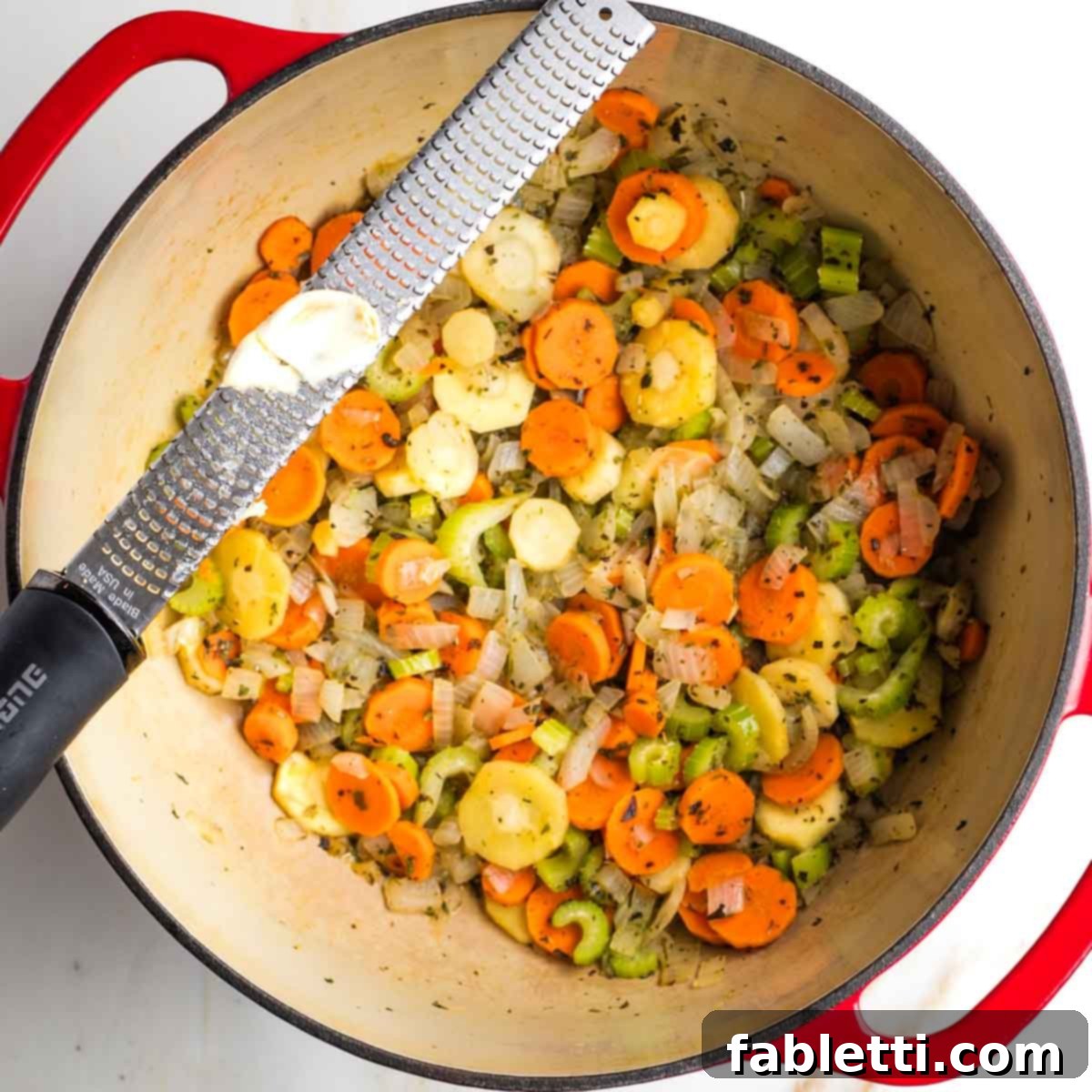 Hearty Fall Vegan Minestrone 7 Grating garlic over a dutch oven with sauteed veggies.