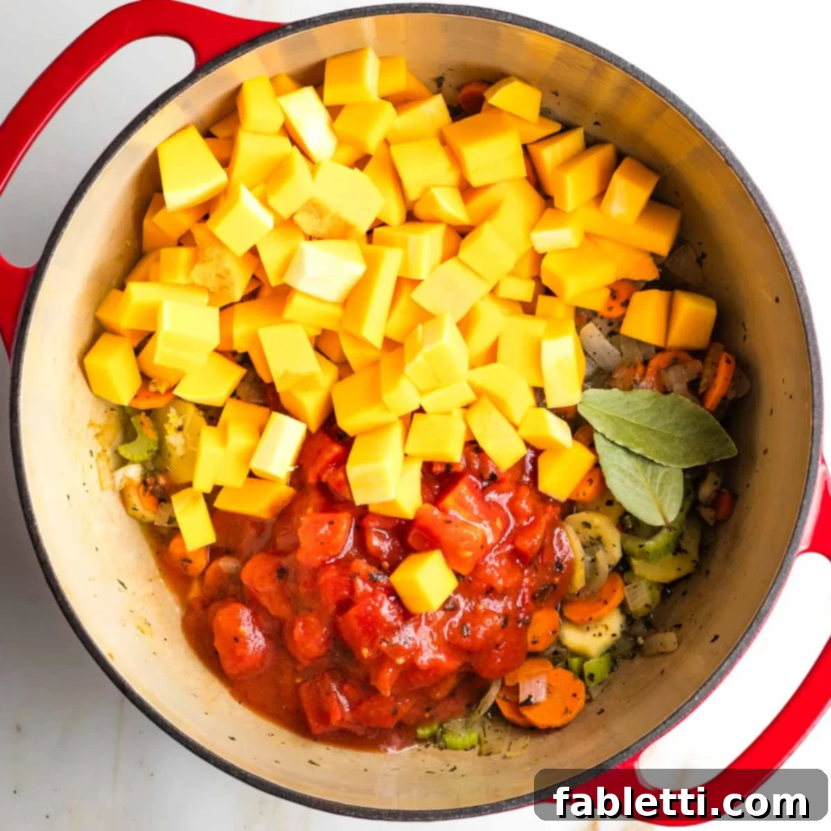 Hearty Fall Vegan Minestrone 8 Diced butternut squash and canned tomatoes plus bay leaves in a dutch oven with sauteed veggies.
