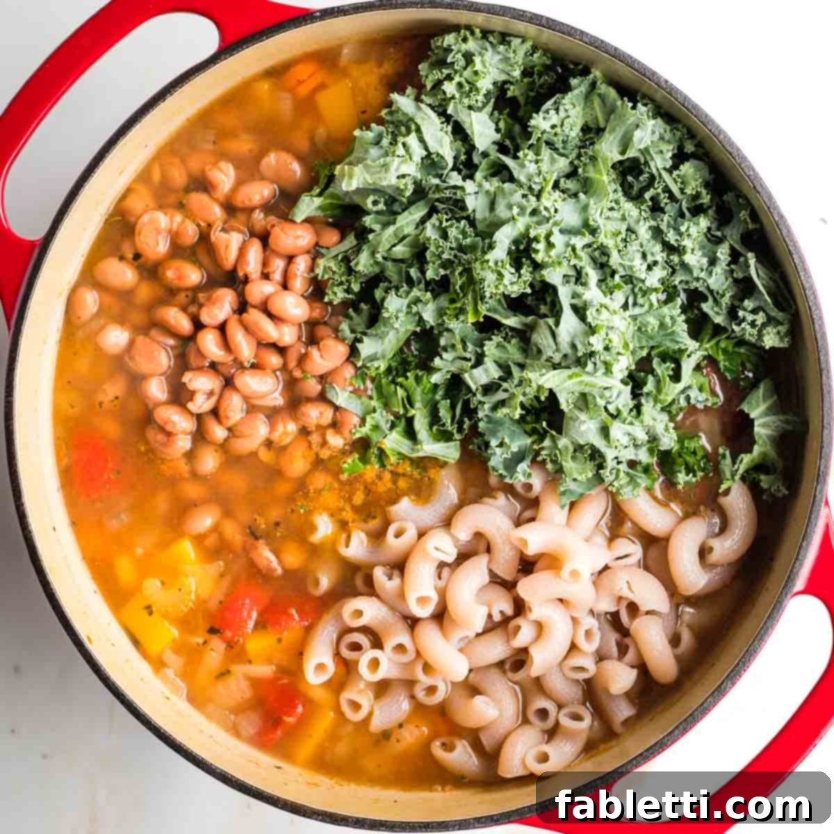 Hearty Fall Vegan Minestrone 10 Chopped kale, pinto beans and cooked pasta in a pot of veggie soup.