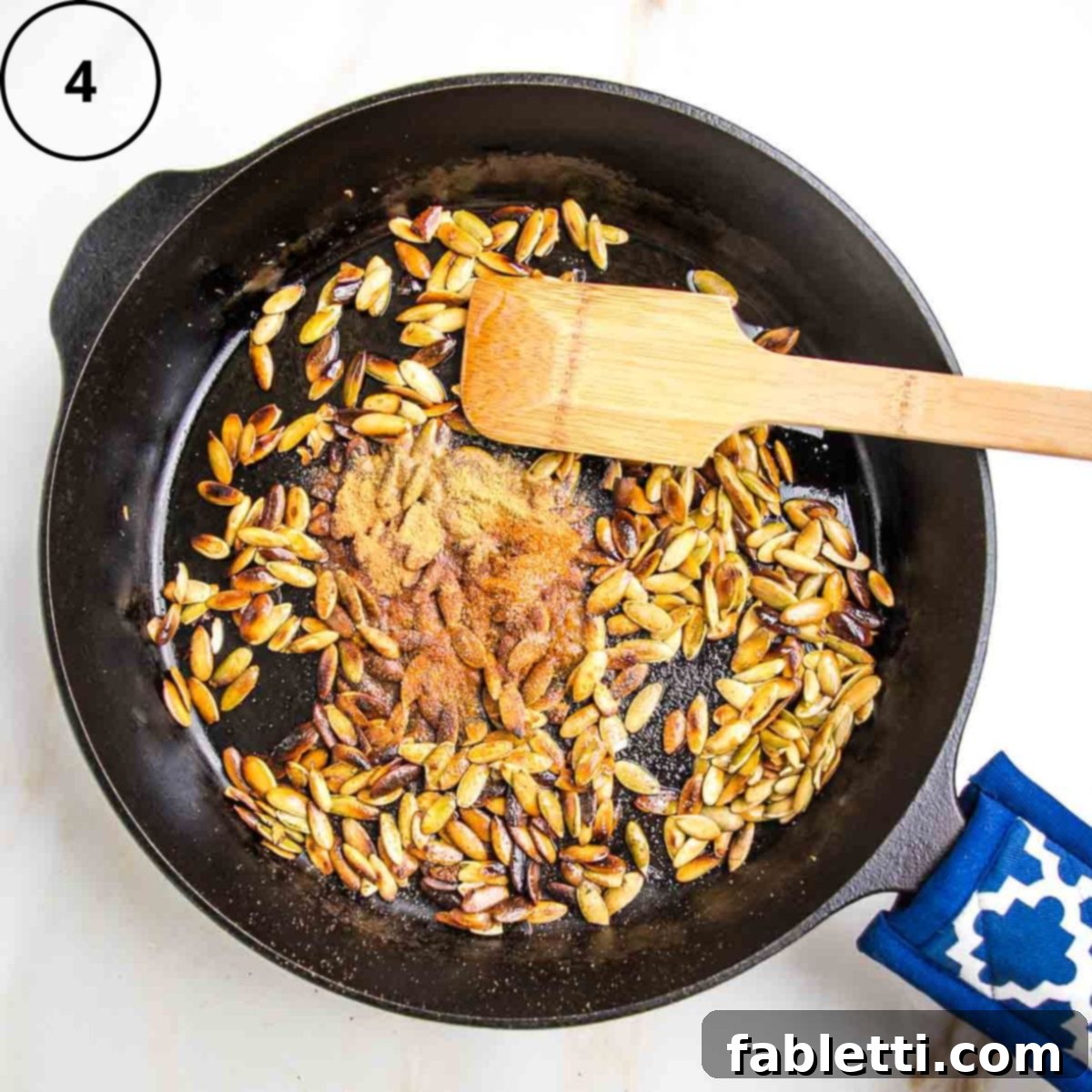 Velvety Vegan Butternut Bliss 13 Toasted pumpkin seeds in a cast iron skillet with spices sprinkled onto the center.