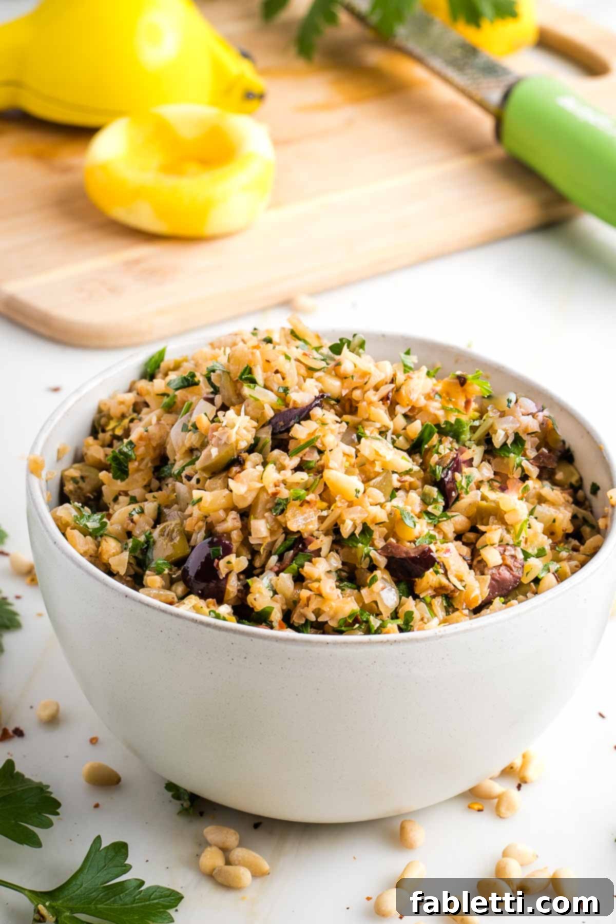 Mediterranean Cauliflower Medley 2 Flavorful Mediterranean Cauliflower Rice with olives, pine nuts, and fresh parsley, garnished with lemon wedges.