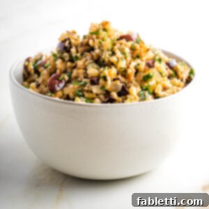 Mediterranean Cauliflower Medley 11 Cauliflower rice with olives, pine nuts and parsley in a white bowl.