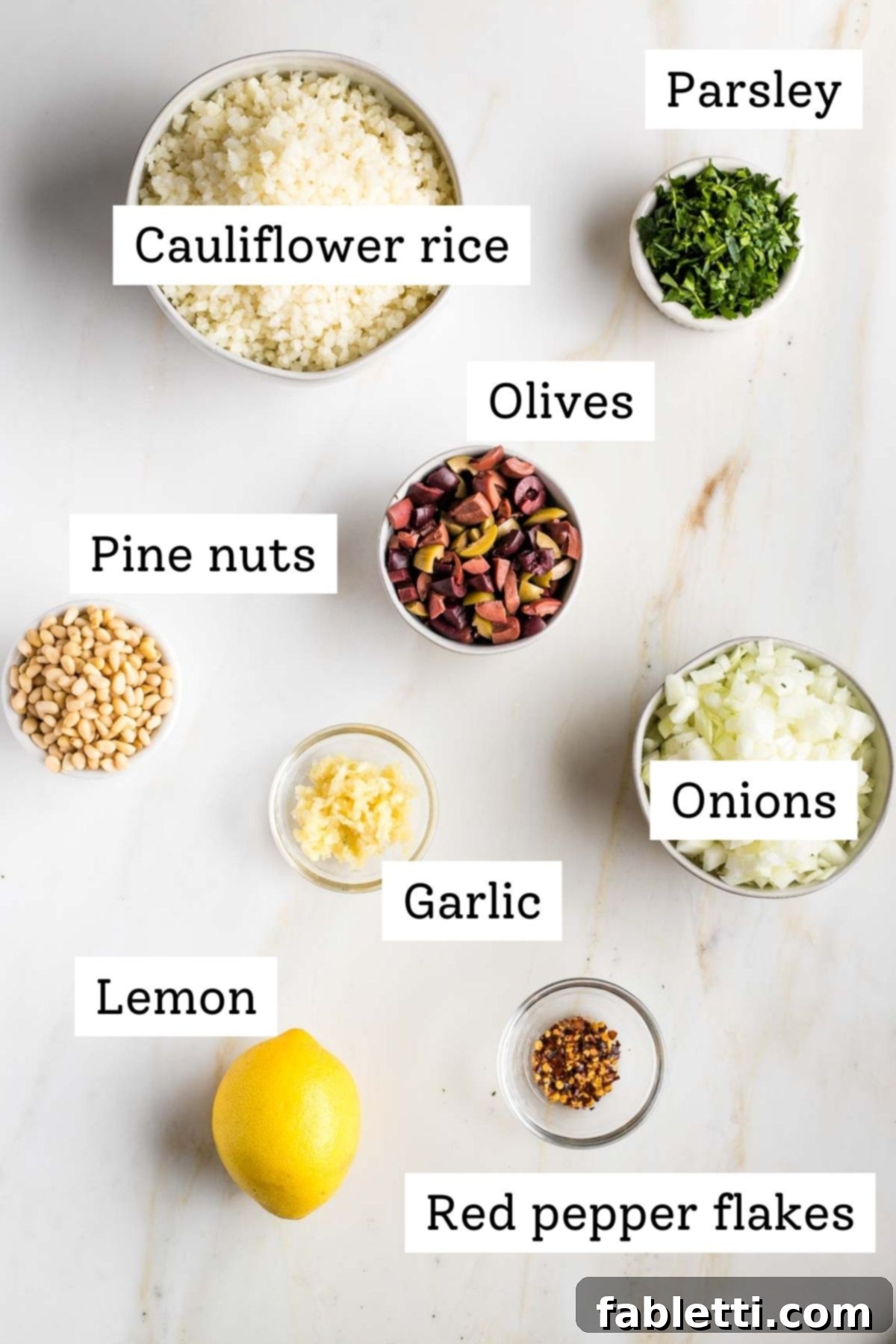 Mediterranean Cauliflower Medley 3 Labeled ingredients for Mediterranean Cauliflower Rice: riced cauliflower, fresh parsley, olives, pine nuts, onions, garlic, lemon, red pepper flakes.