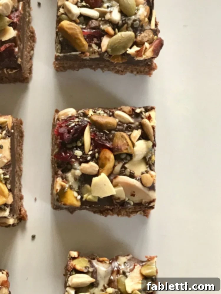 Energy-Packed Chocolate Oat Bars 3 Top view of an oatmeal bar covered in melted chocolate, swirled with tahini, and sprinkled with a colorful trail mix.