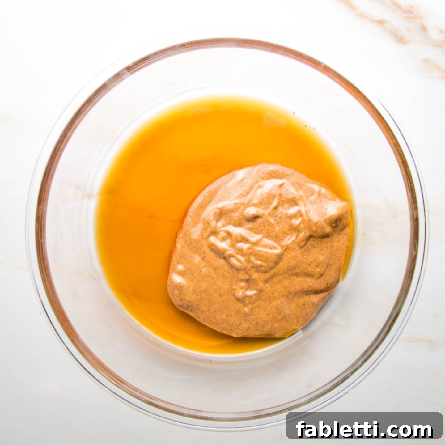 Almond Gem Cookies 5 Smooth almond butter, pure maple syrup, and almond extract combined in a clear glass mixing bowl.