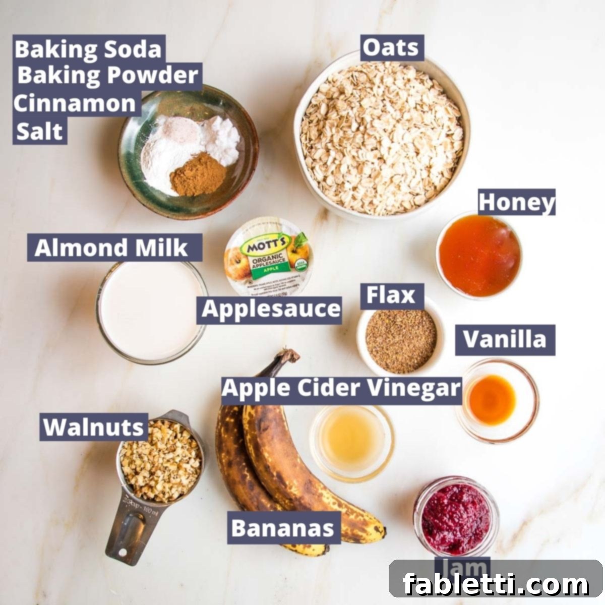 Ingredients for Jam Muffins labeled: oats, honey, flax, vanilla, apple cider vinegar, jam, bananas, chopped walnuts, almond milk, applesauce, baking soda, baking powder, cinnamon, salt