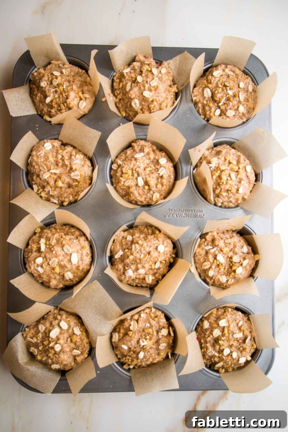 Muffin tin, lined with parchment strips and filled with oatmeal batter.