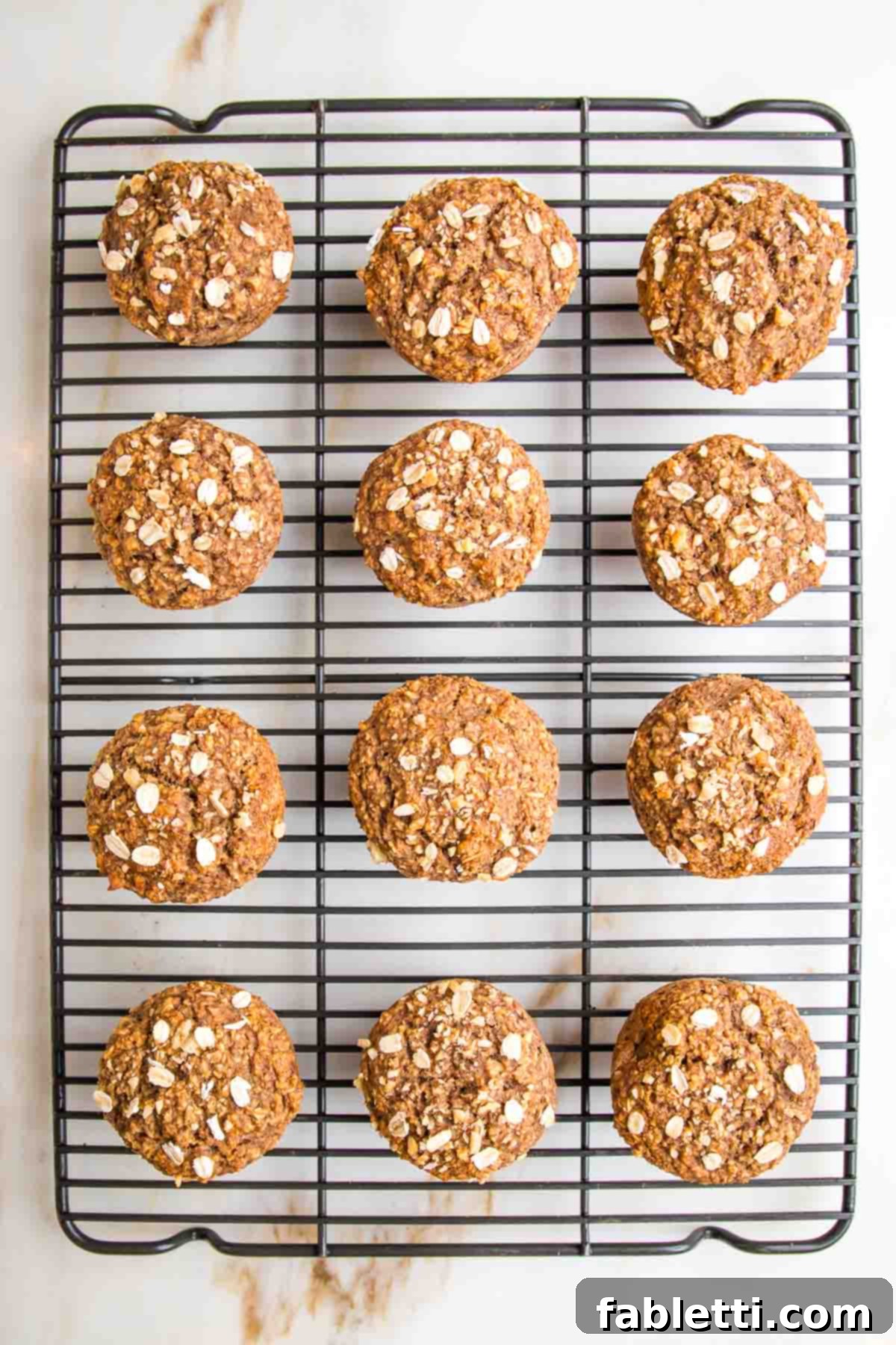 a dozen oatmeal muffins on a wire rack. 