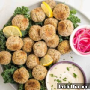 Deliciously Healthy Baked Falafel 21 A plate generously filled with golden-brown baked falafel balls, accompanied by a small dish of creamy tahini sauce and another small bowl of vibrant pickled red onions, creating an inviting meal.