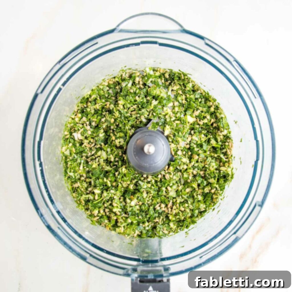 Deliciously Healthy Baked Falafel 6 The processed mixture of herbs, nuts, onions, and garlic in a food processor bowl, now finely chopped and fragrant, forming the base for the falafel.