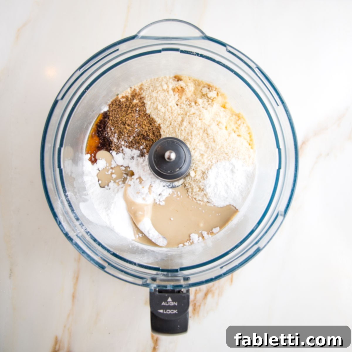 Food processor bowl filled with ingredients for hamentaschen: almond flour, arrowroot, ground flax, tahini, maple syrup