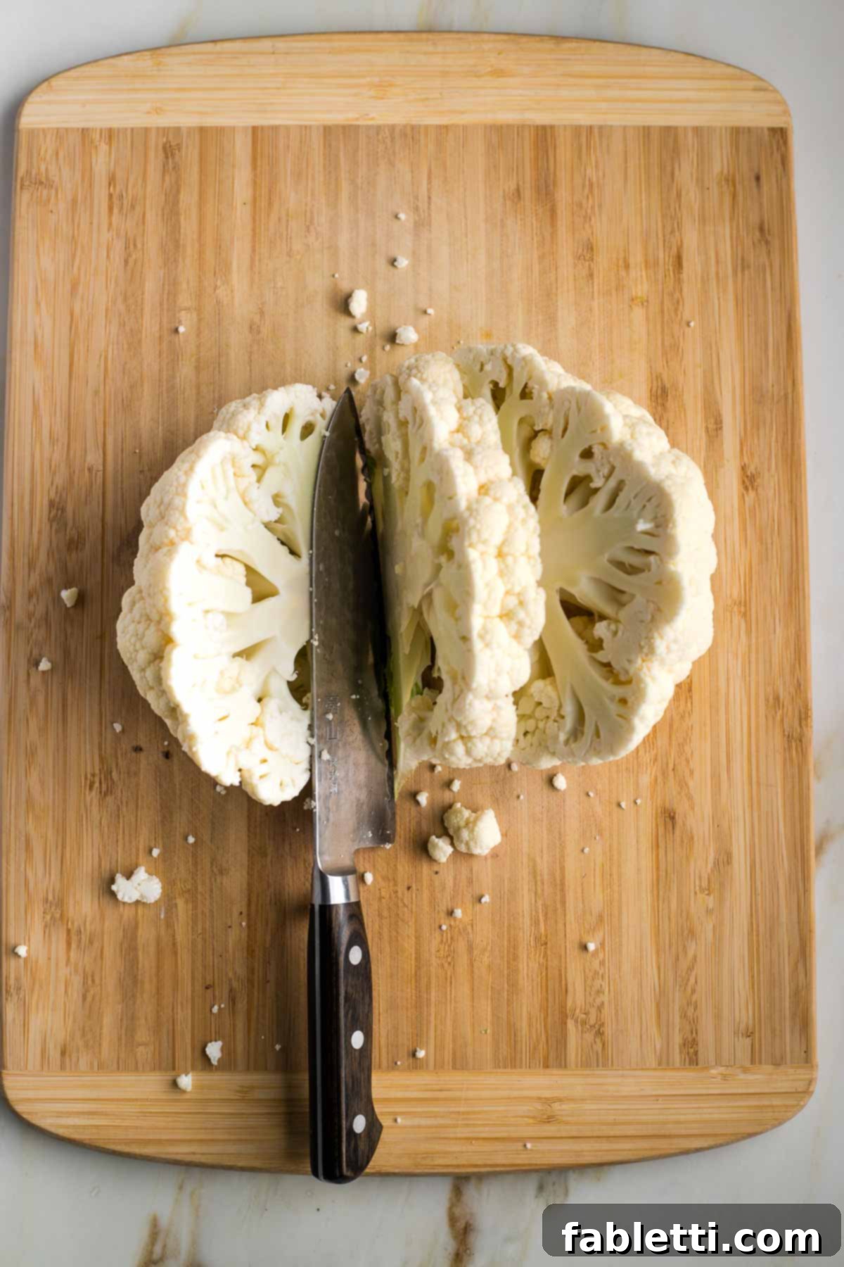Golden Seared Cauliflower Steaks with Herbaceous Chimichurri 8 Cauliflower half on a cutting board, ready for slicing.