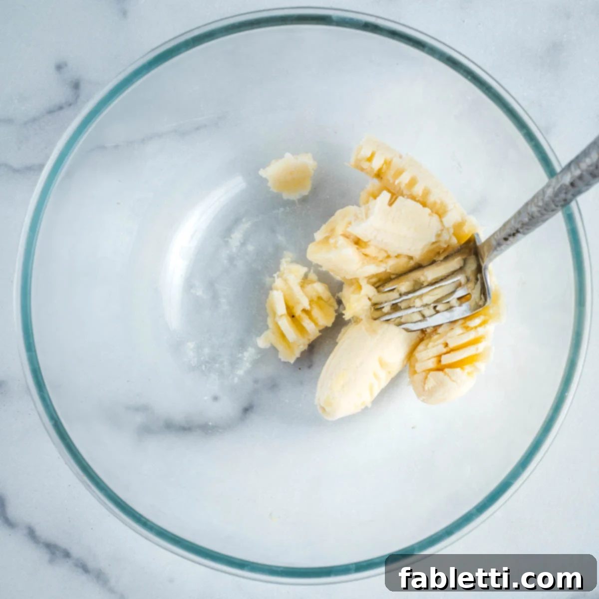 Delightful Gluten-Free Almond Carrot Muffins 4 Mashing a ripe banana in a mixing bowl with a fork.