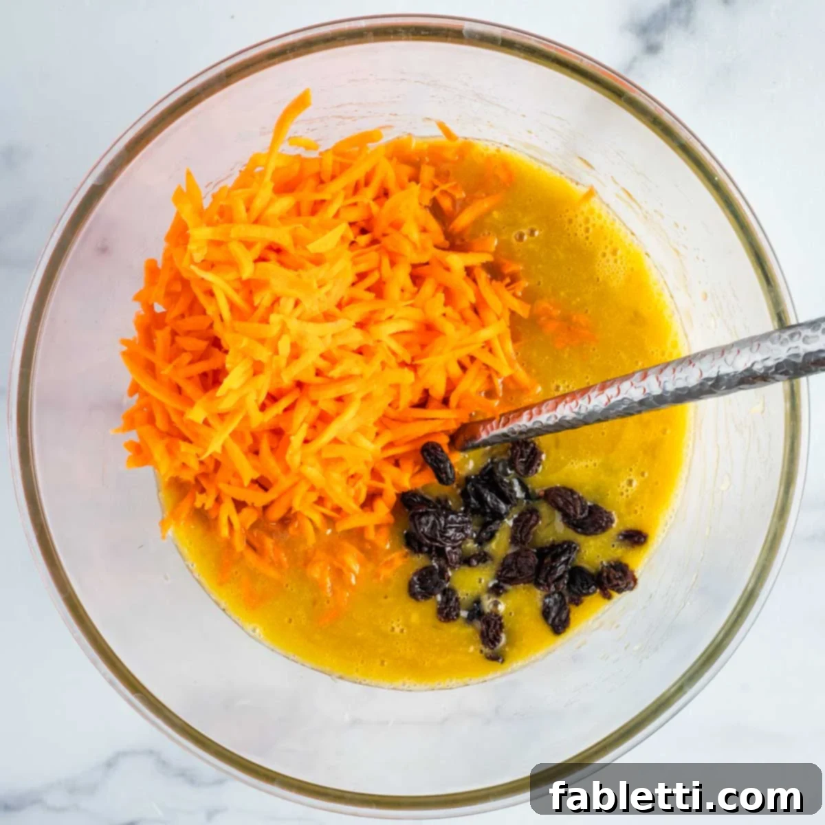 Delightful Gluten-Free Almond Carrot Muffins 8 Shredded carrots and raisins being added to the muffin batter.