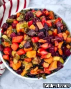 Effortless Sweet Potato and Carrot Tzimmes 10 A bowl filled with vibrant, roasted, cubed vegetables like beets, Brussels sprouts, carrots, and sweet potatoes, showcasing the delicious Tzimmes.