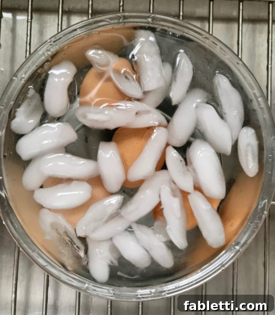 Perfectly boiled eggs cooling rapidly in a bowl of ice water to stop cooking and aid in easy peeling