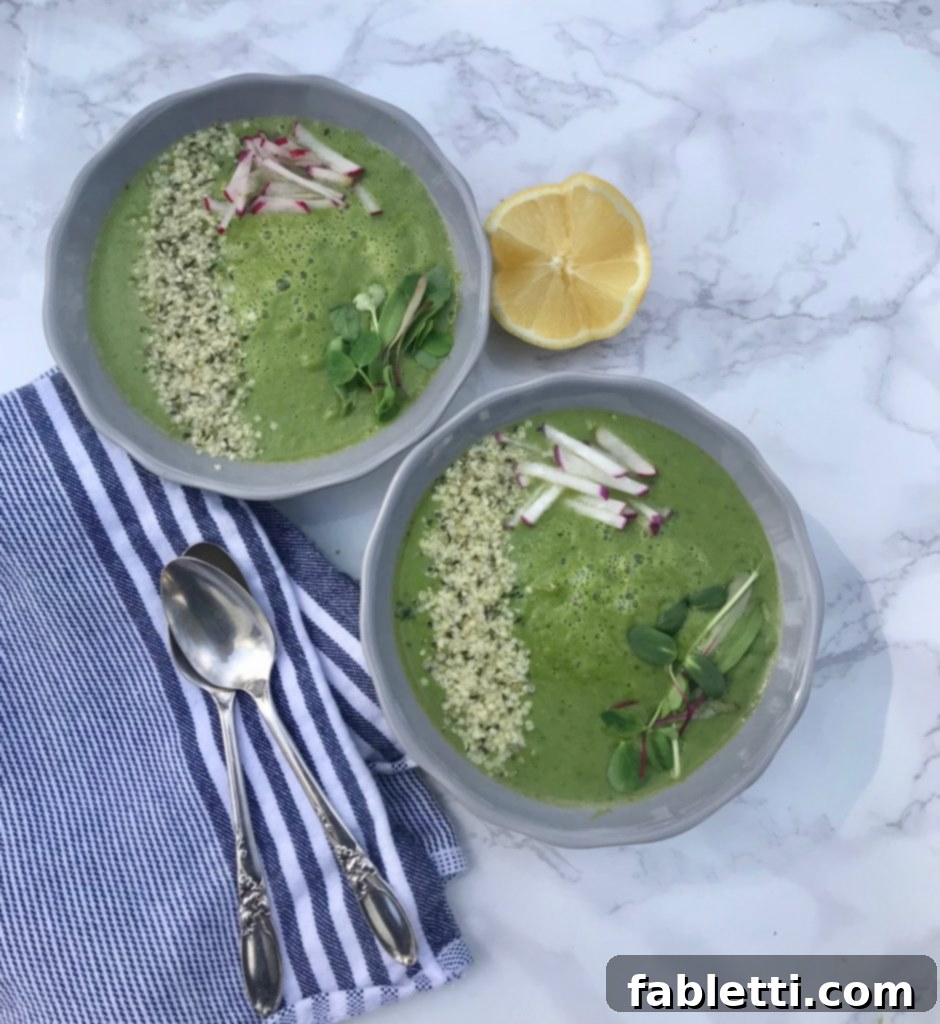 A bowl of creamy Spring Greens Soup garnished with fresh herbs and a drizzle of olive oil, ready to eat.