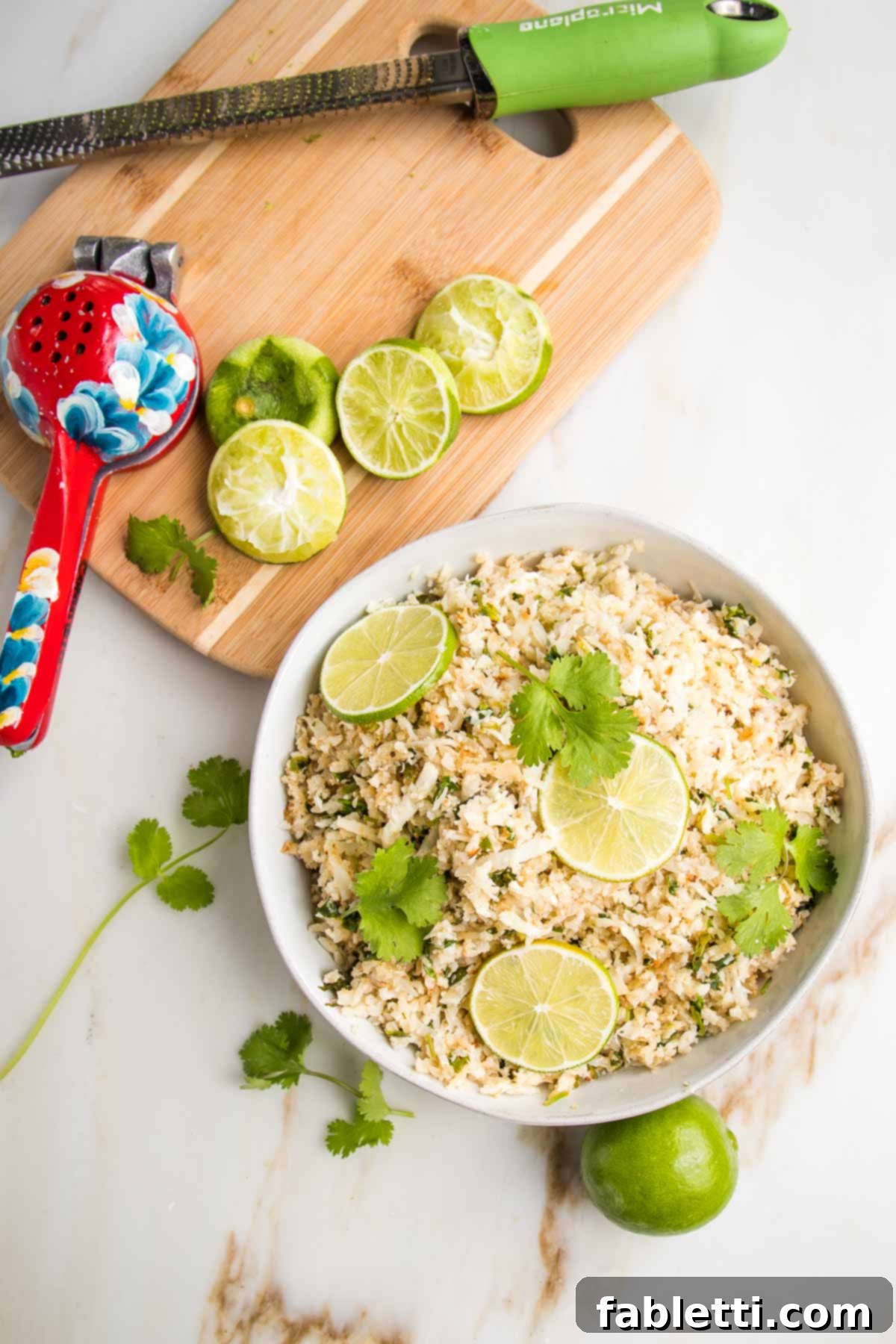 Quick Skillet Cauliflower Rice 11 Cauliflower Rice in a bowl with lime slices and cilantro. In the background is a cutting board with limes zested and squeezed.