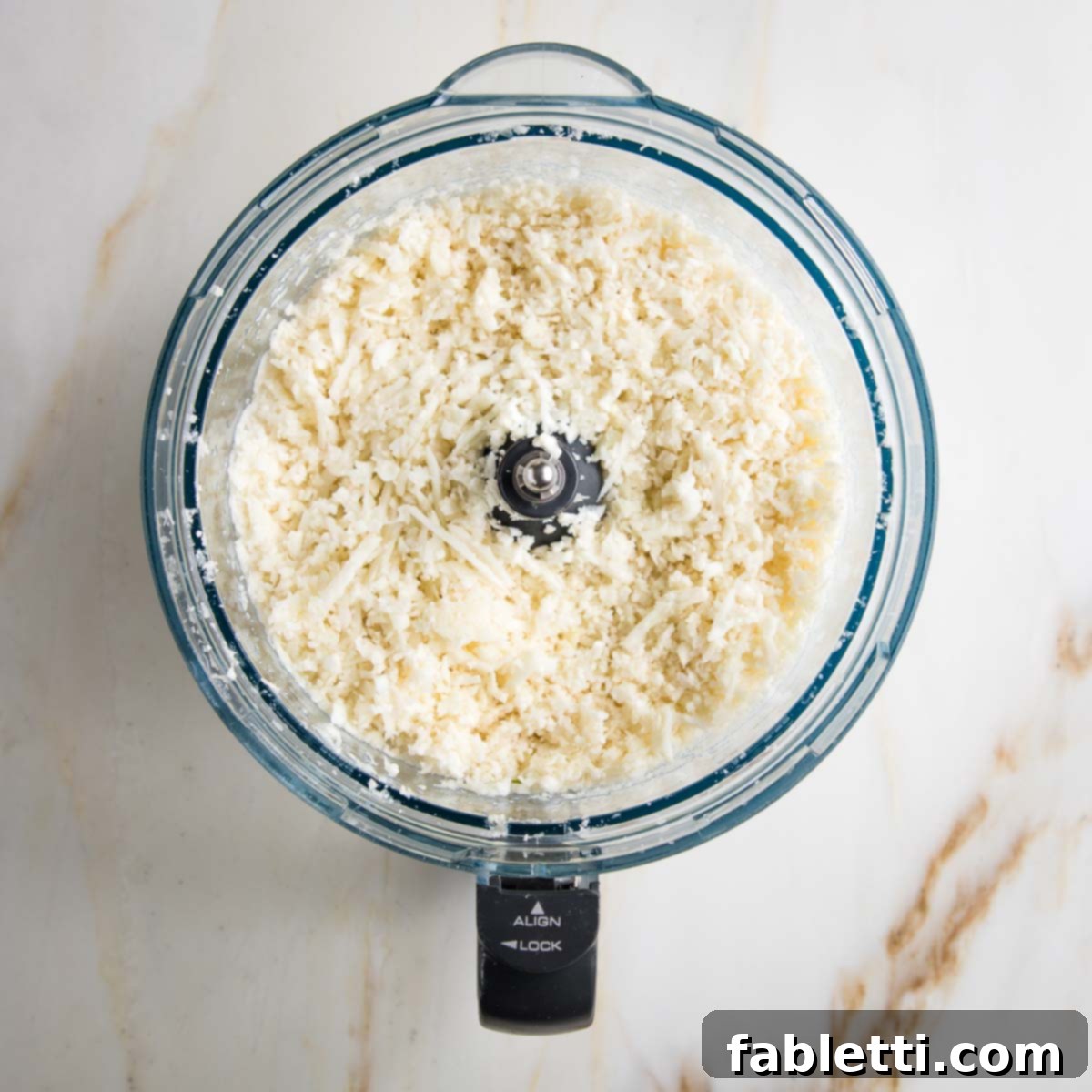 Quick Skillet Cauliflower Rice 6 Riced cauliflower in the bowl of a food processor.