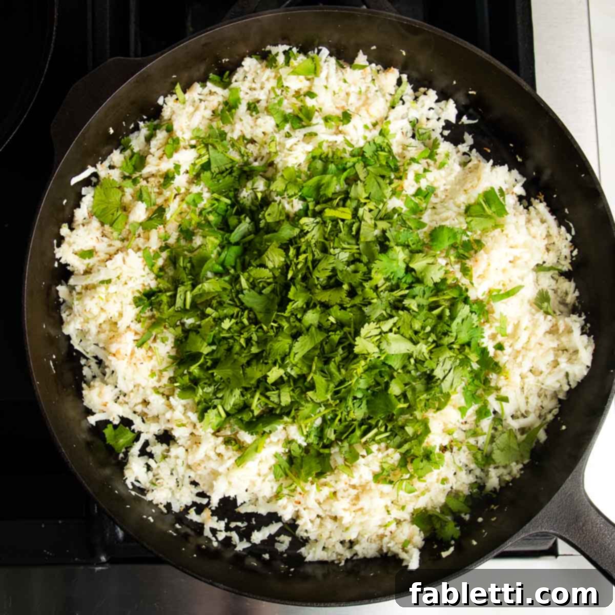Quick Skillet Cauliflower Rice 8 Cast iron skillet with cauli-rice and a bunch of chopped cilantro on top.