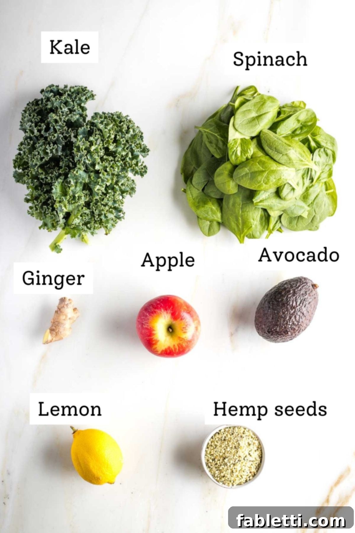 Avocado Kale Superfood Smoothie 3 A beautifully arranged spread of fresh, vibrant smoothie ingredients: dark green kale and spinach, a bright green apple, a zesty lemon, pungent ginger, a creamy avocado half, and nutrient-rich hemp seeds, ready for blending.