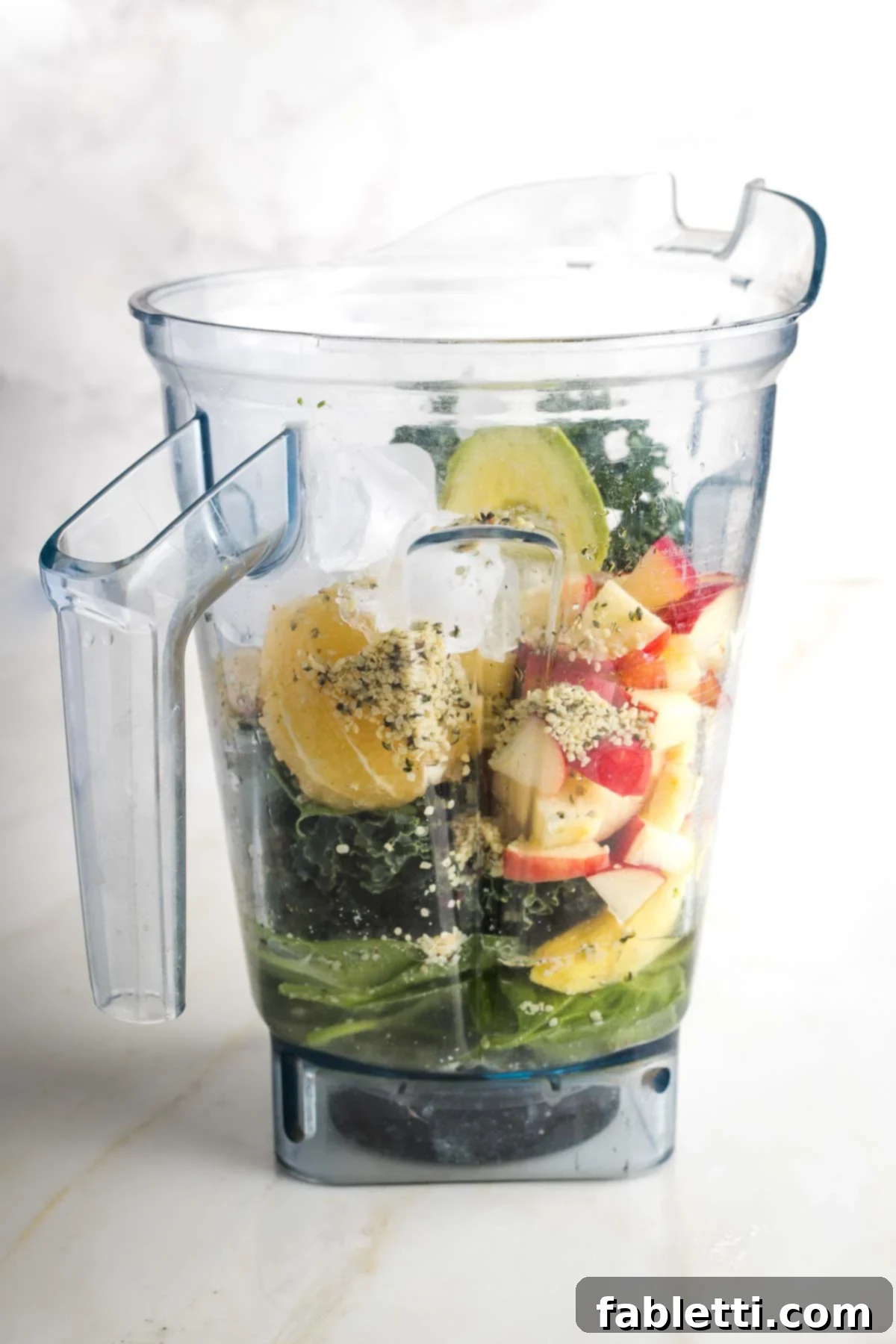 Avocado Kale Superfood Smoothie 6 A clear blender pitcher showcasing the vibrant green smoothie ingredients, now joined by water and ice cubes, creating a promising blend of health and refreshment.