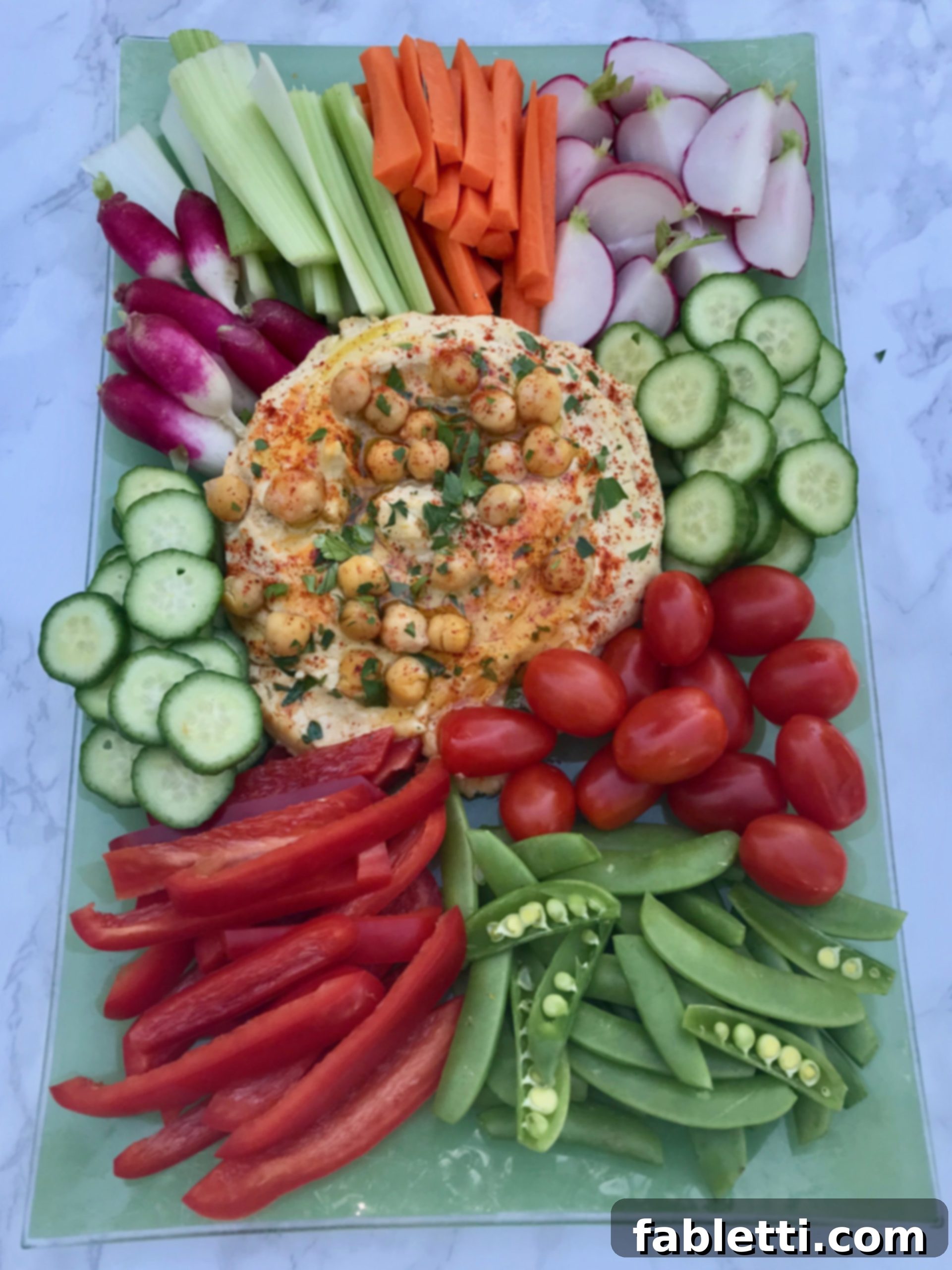 A large platter of fresh vegetables and oil-free hummus, showing a healthy snack option.