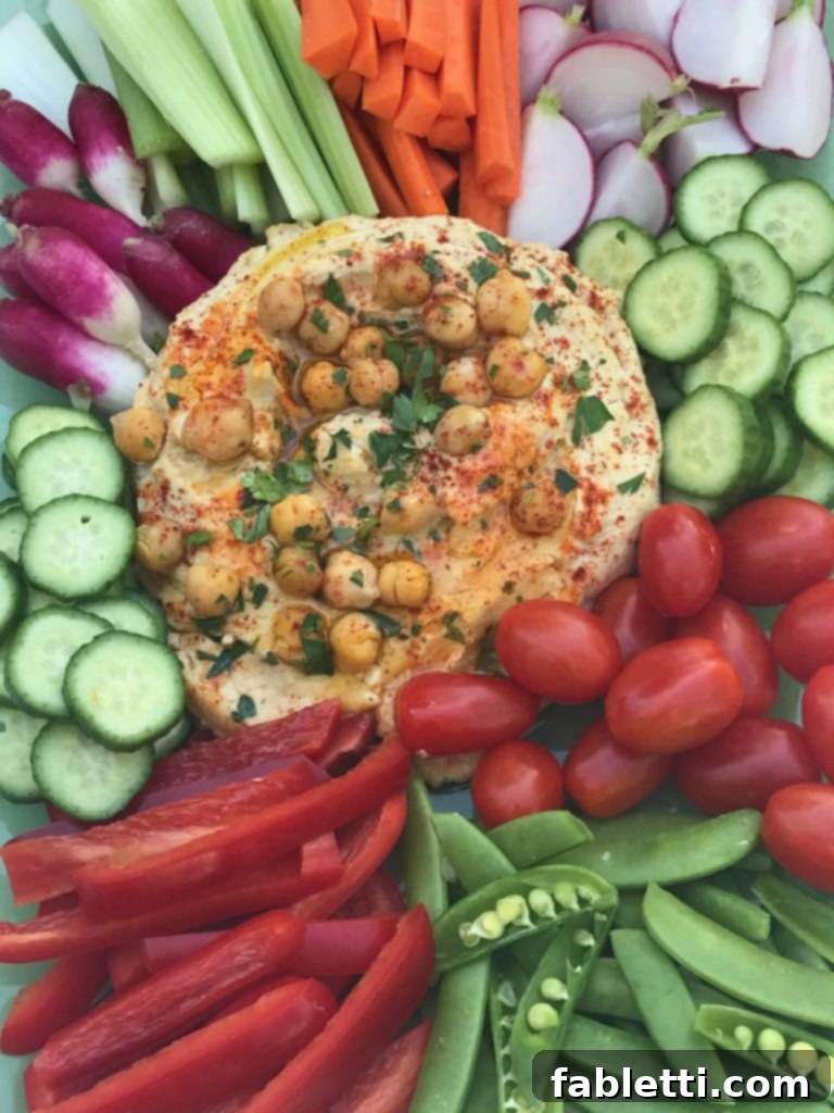A bowl of oil-free hummus with a side of pita bread and fresh herbs.