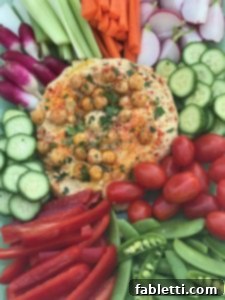 Hummus surrounded by colorful veggies.