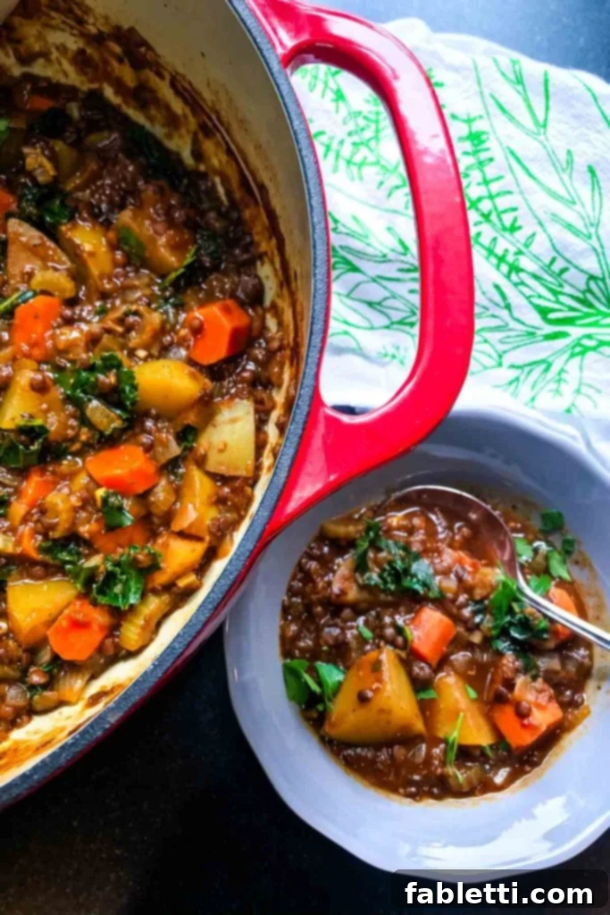 Rich vegan beef stew in a Dutch oven and a serving bowl, showcasing lentils, carrots, potatoes, kale, and a thick, brown, savory broth.
