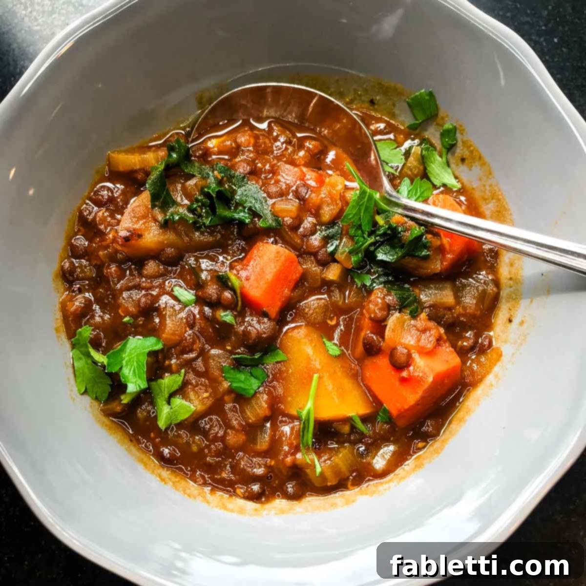 Finished vegan stew, served in a bowl, garnished with fresh herbs, and a Dutch oven in the background.