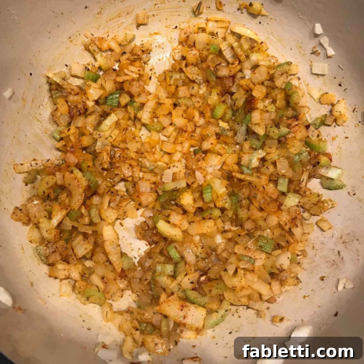 Sautéing diced onion and celery in a Dutch oven, releasing aromatic flavors.