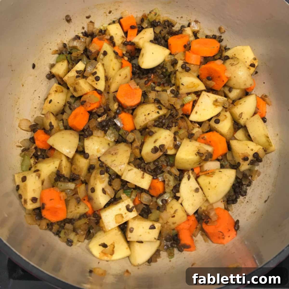 Adding dried lentils and minced garlic to the sautéed vegetables and spices.