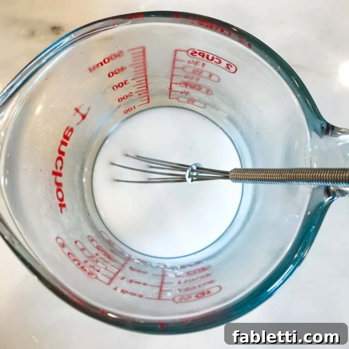 Preparing an arrowroot powder slurry with water in a small bowl.