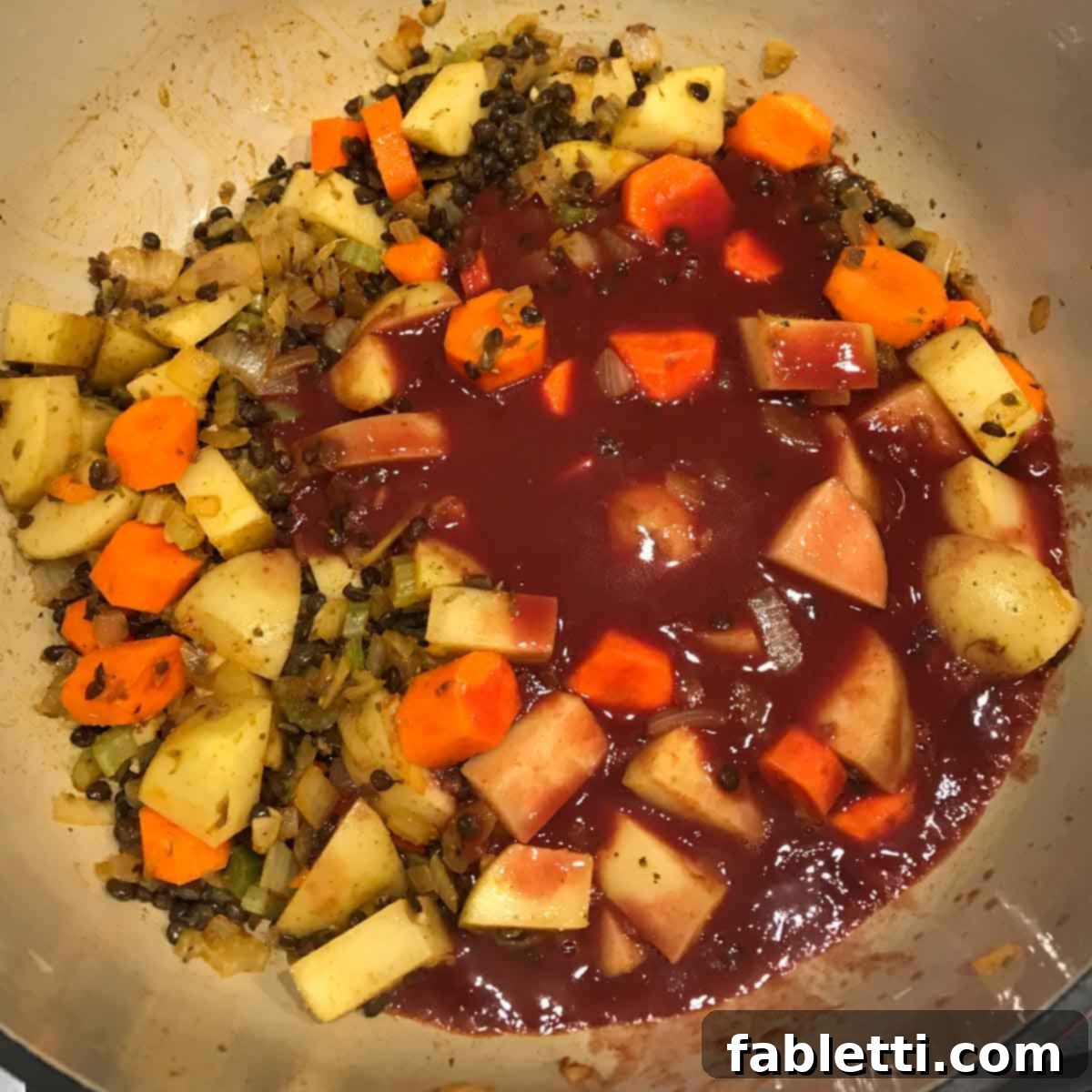 Adding chopped carrots and potatoes to the stew pot, followed by deglazing with red wine and vegan Worcestershire sauce.