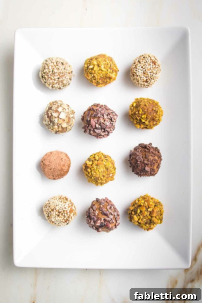 Pumpkin Spice Truffles 4 A white rectangular plate displaying pumpkin balls individually rolled in various crushed nuts or seeds, showcasing different topping options.