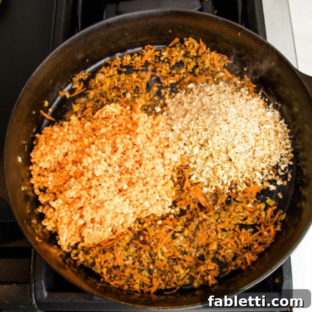 Hearty Vegan Bolognese over Squash Strands 11 Red lentils and finely chopped walnuts being added to a cast iron pan already filled with sautéed mushrooms, carrots, celery, onions, and spices, ready for mixing.