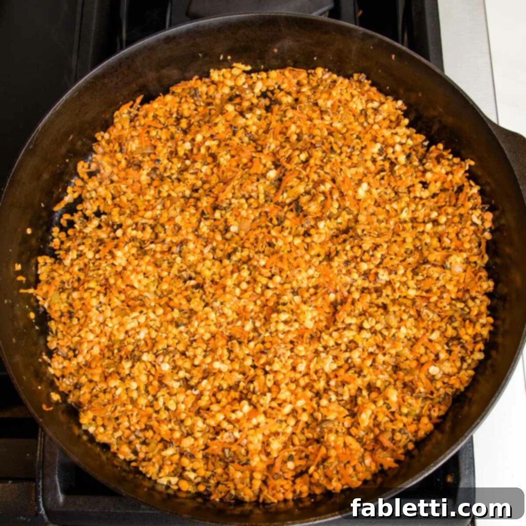 Hearty Vegan Bolognese over Squash Strands 12 A cast iron skillet filled with sautéed vegetables and lentils, with red wine being poured in to deglaze the pan.
