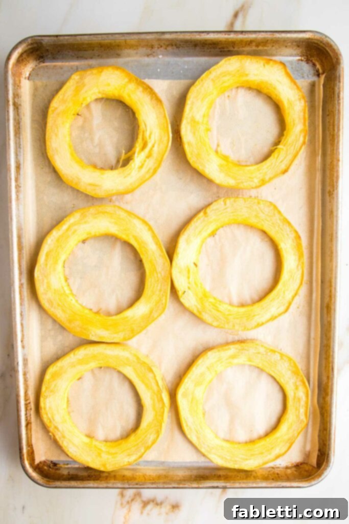 Hearty Vegan Bolognese over Squash Strands 17 Roasted spaghetti squash rings on a parchment-lined baking tray, golden brown and tender, indicating they are perfectly cooked.