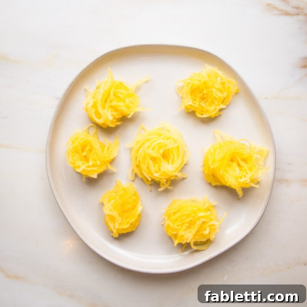 Hearty Vegan Bolognese over Squash Strands 22 A pristine white rimmed plate with twirled sections of perfectly cooked spaghetti squash, ready to be topped with sauce.