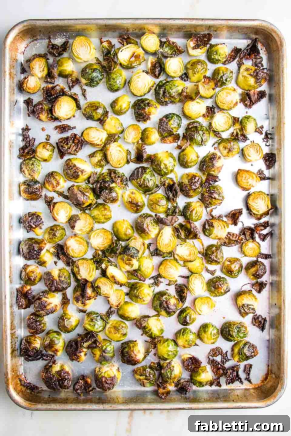 Honey Sriracha Glazed Crispy Roasted Brussels Sprouts 6 A close-up of a baking tray filled with perfectly oven-roasted Brussels sprouts, golden brown with crispy, caramelized edges, indicating readiness.