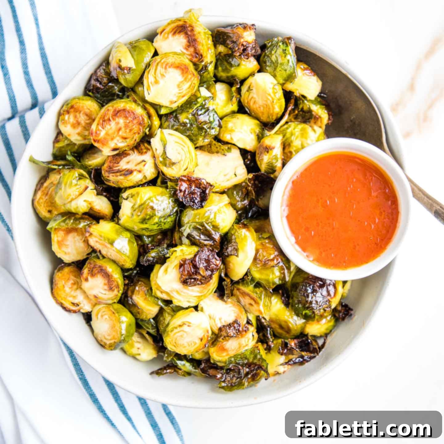 Honey Sriracha Glazed Crispy Roasted Brussels Sprouts 9 A close-up shot emphasizing the beautiful golden-brown and slightly charred edges of perfectly roasted Brussels sprouts on a baking sheet, illustrating ideal crispiness.